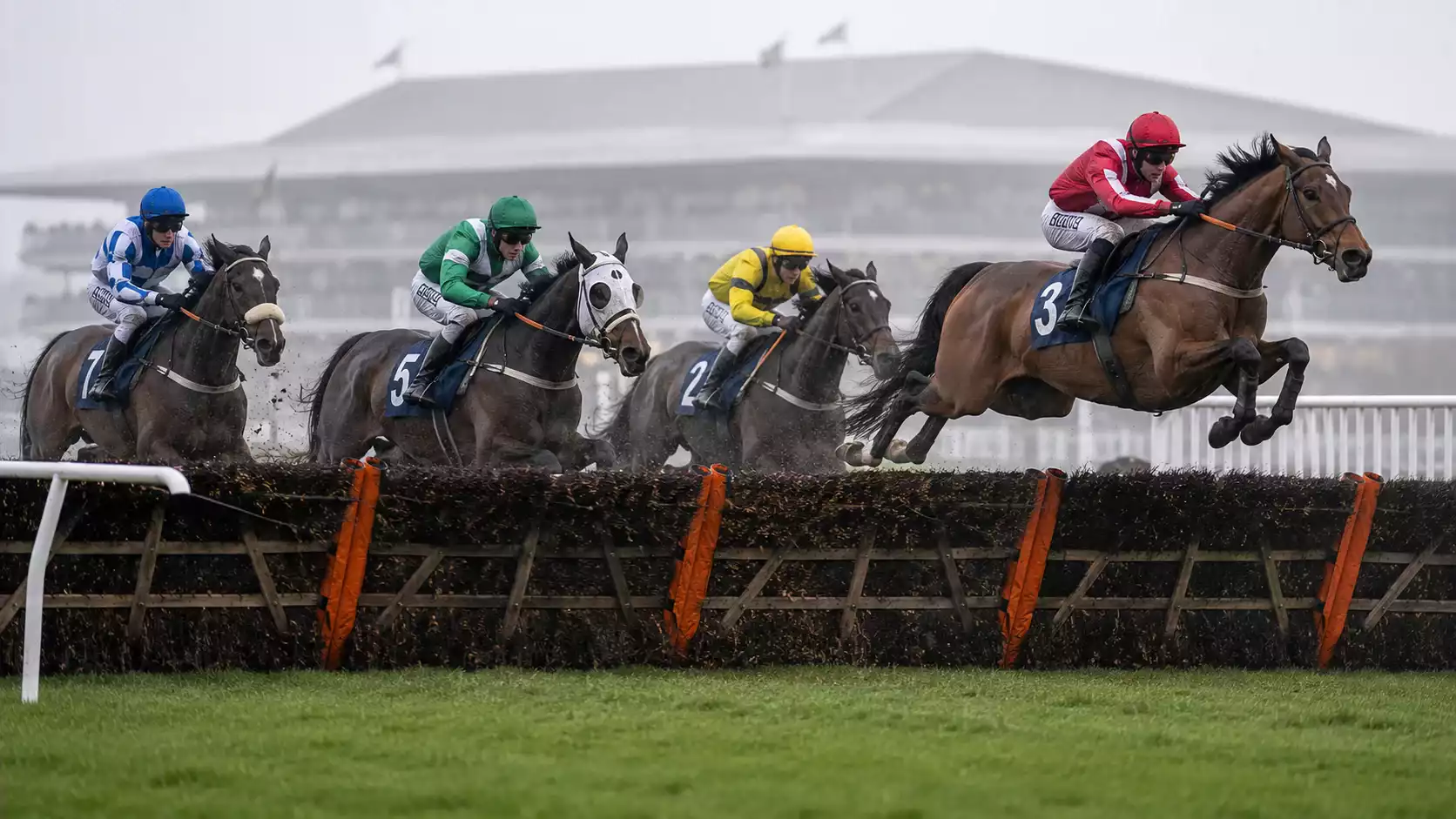 Horses and jockeys jumping a fence at the Grand National at Aintree Racecourse