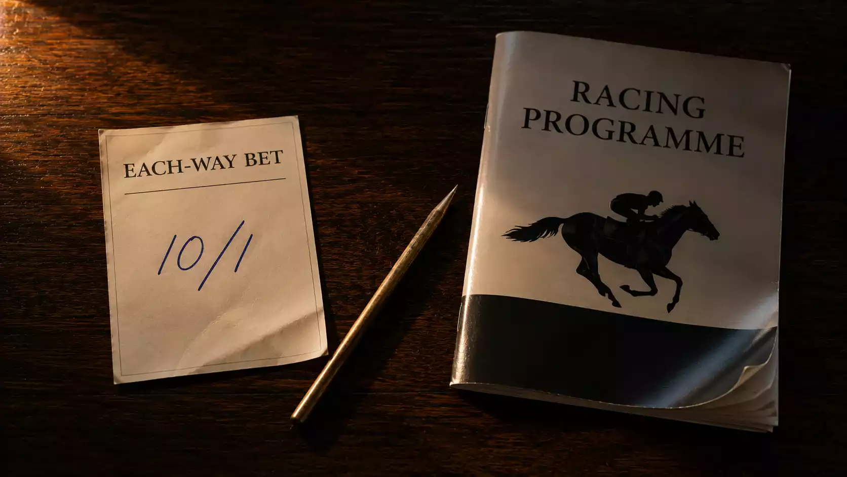 A British betting slip on a desk next to an American racetrack programme, the two formats side by side