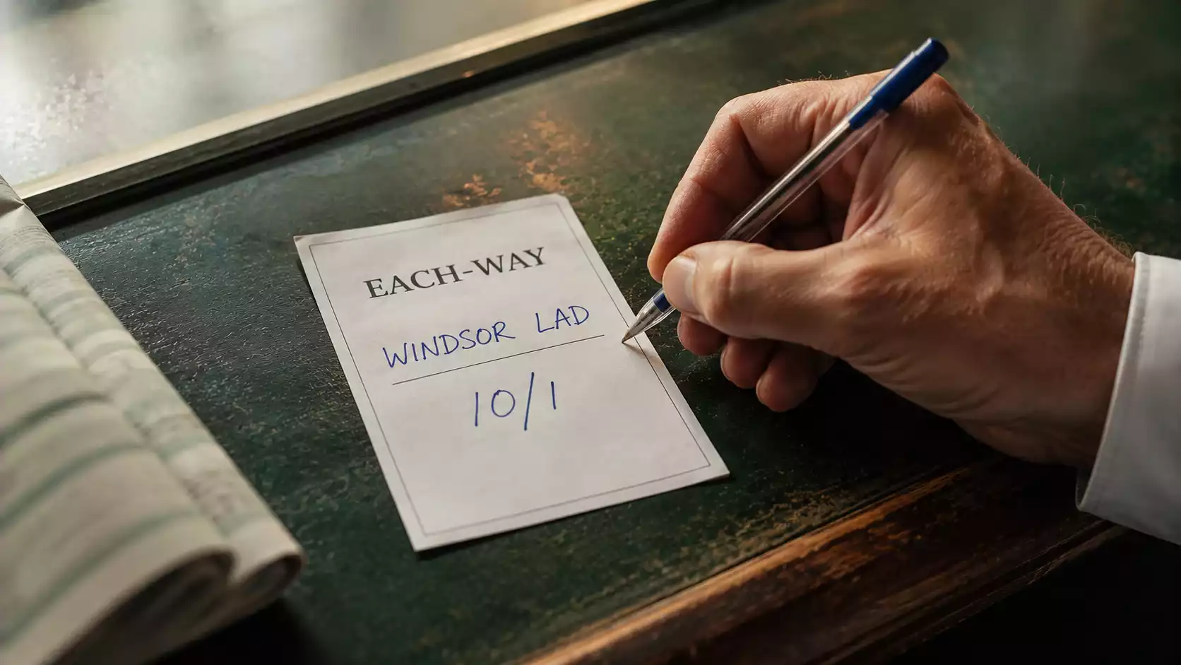A pen completing a UK each-way betting slip on a high-street bookmaker's counter